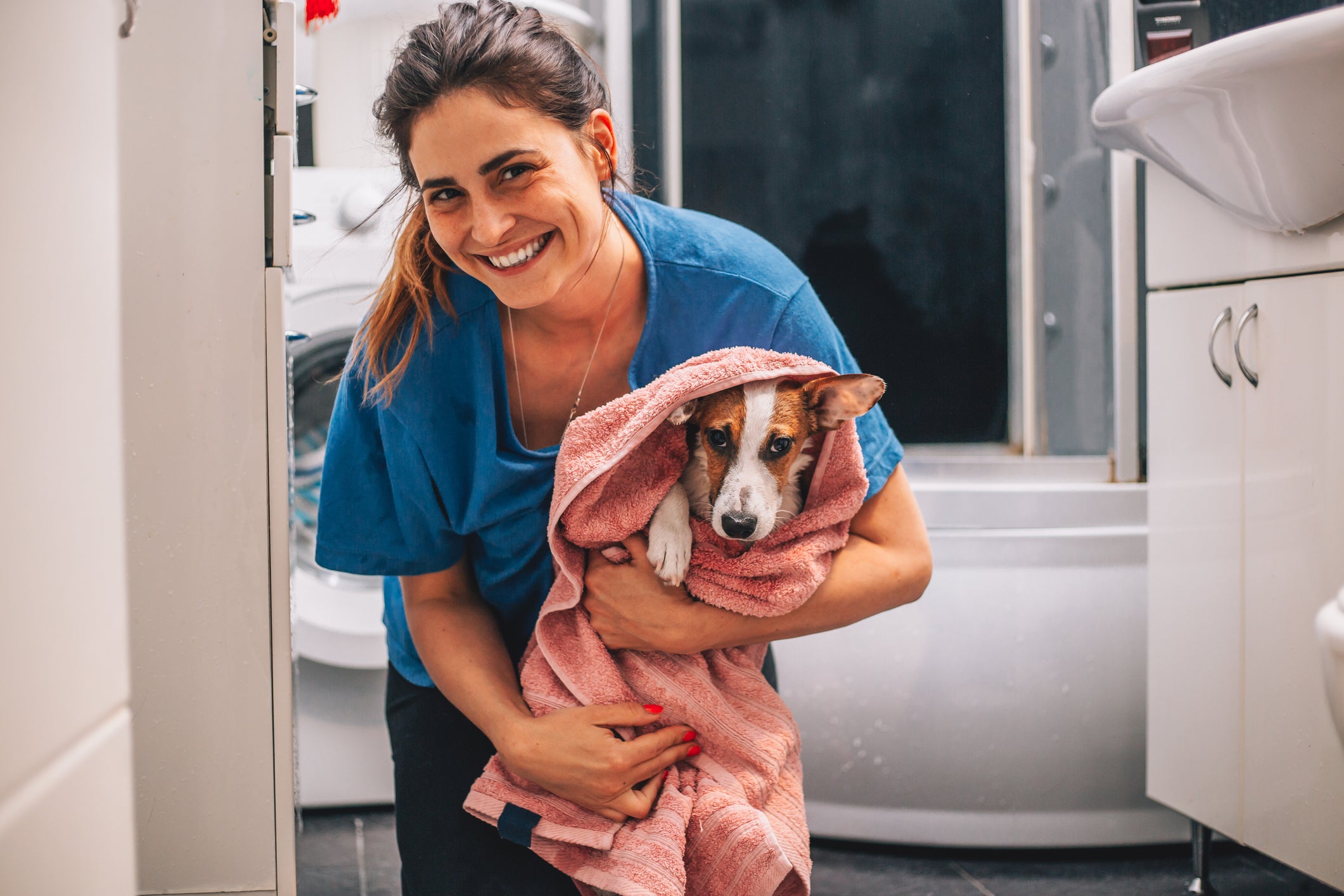 Mulher segurando cachorro no colo enrolado em toalha