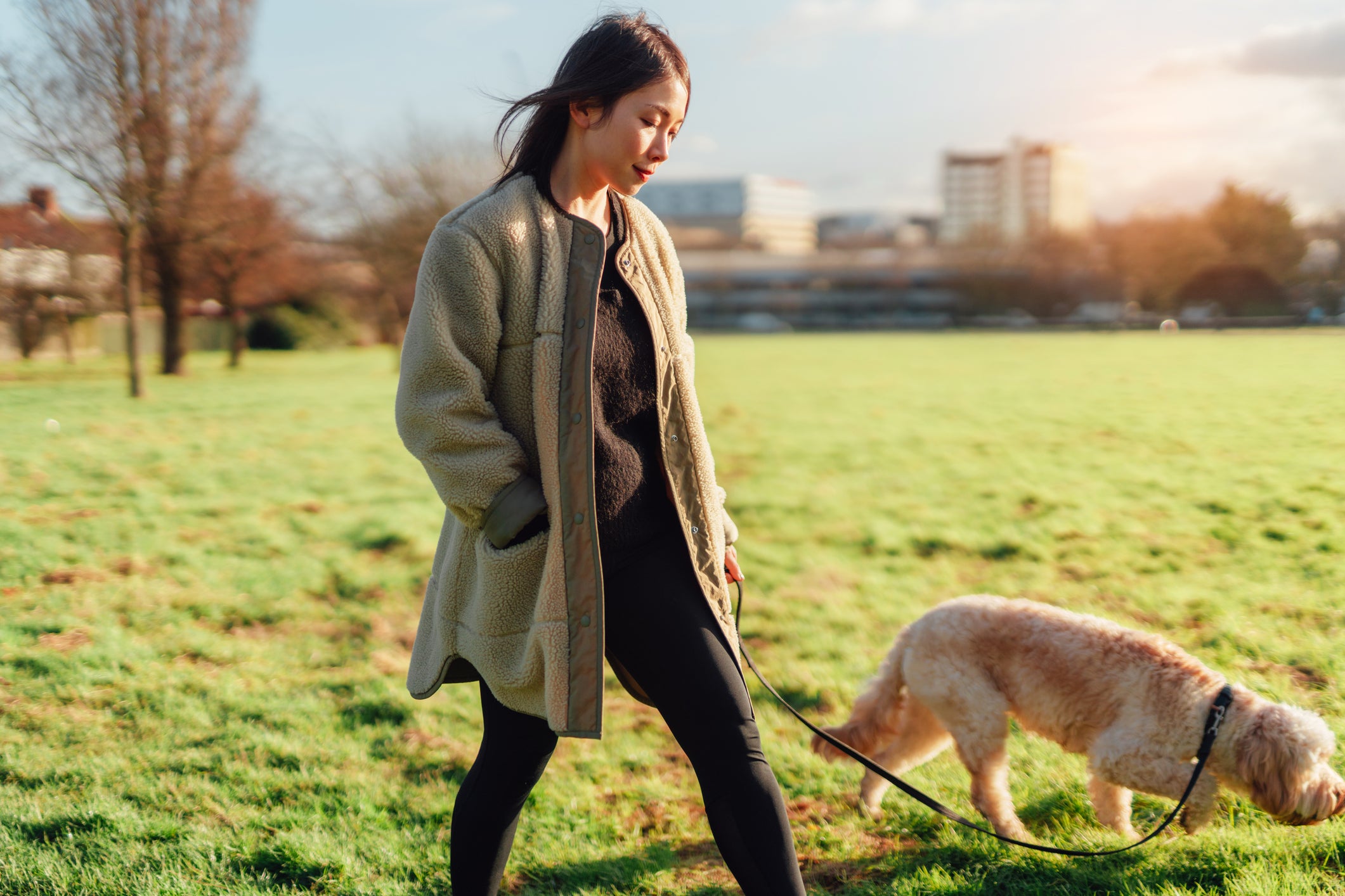 Tutora passeando em parque com seu cachorro na coleira