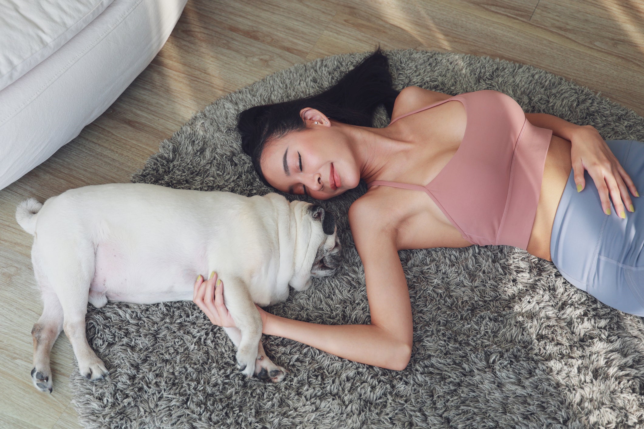 Mulher deitada em tapete junto de cão Pug