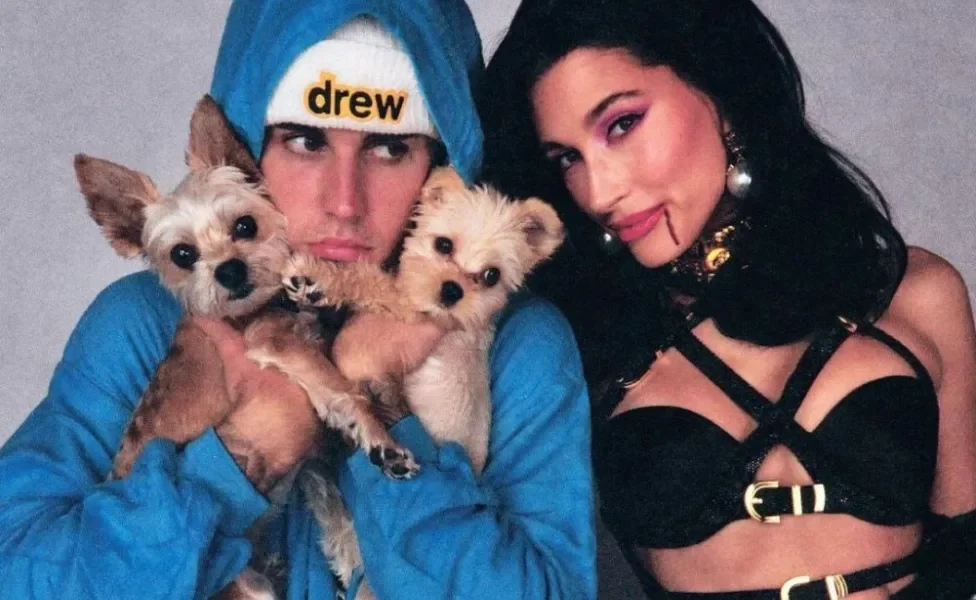 Justin Bieber com casaco azul segurando dois cachorros