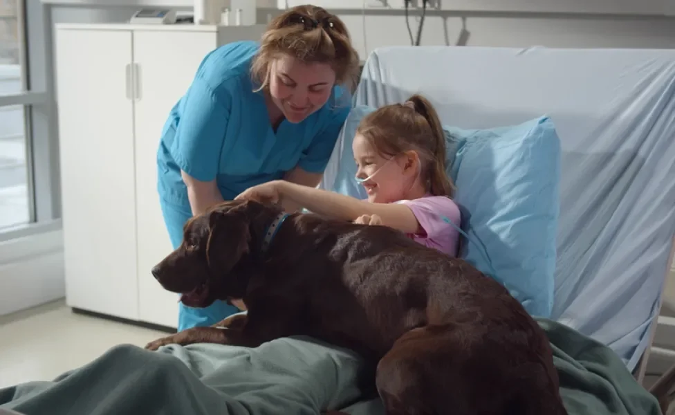 garotinha deitada na cama do hospital com cachorro