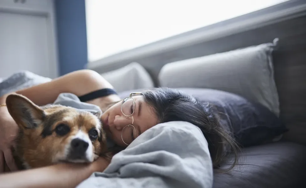 Mulher abraçada e deitada junto de seu cãozinho