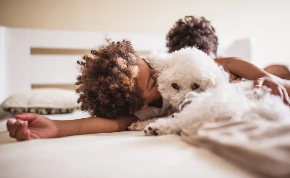 Criança fazendo carinho em cachorrinho branco