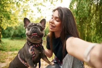 Mulher tirando selfie com cachorro da raça Bulldog em um parque